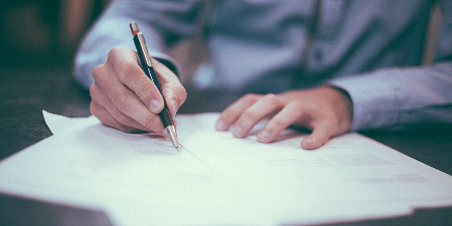 Hands of a man signing a document