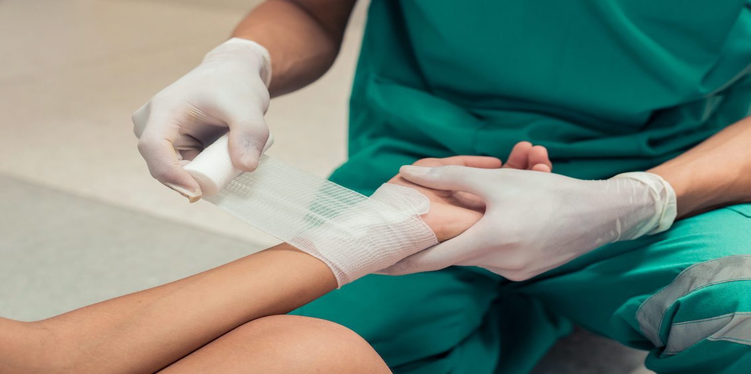 Nurse assists with burn injury at work.