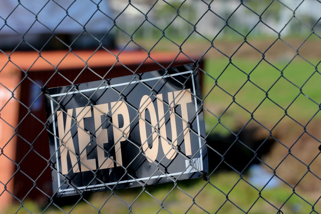 A blue sign with a white text saying ‘KEEP OUT’