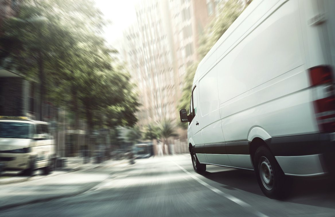 A white delivery van speeding through the streets