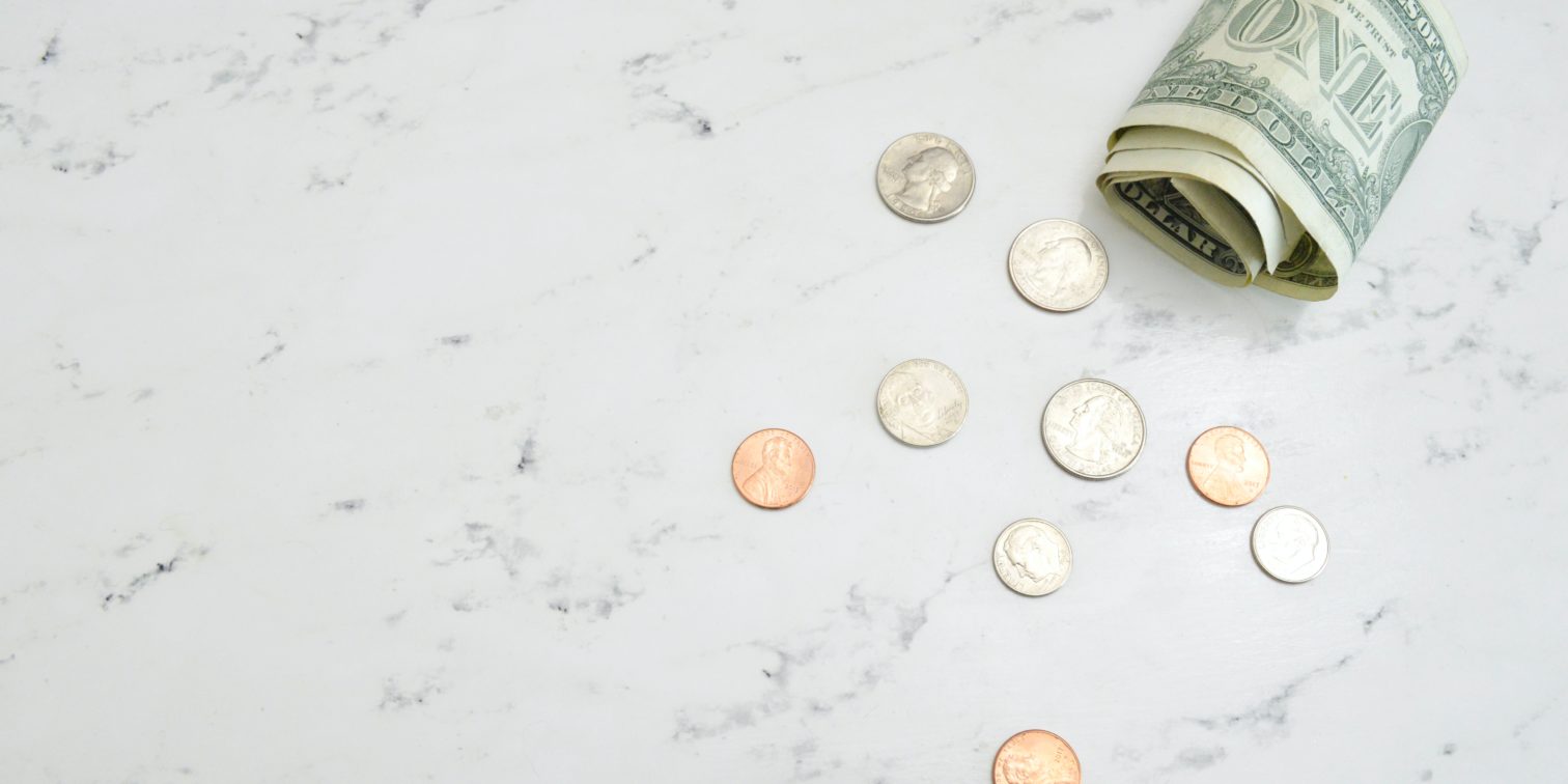 Dollar bills and coins on a white table