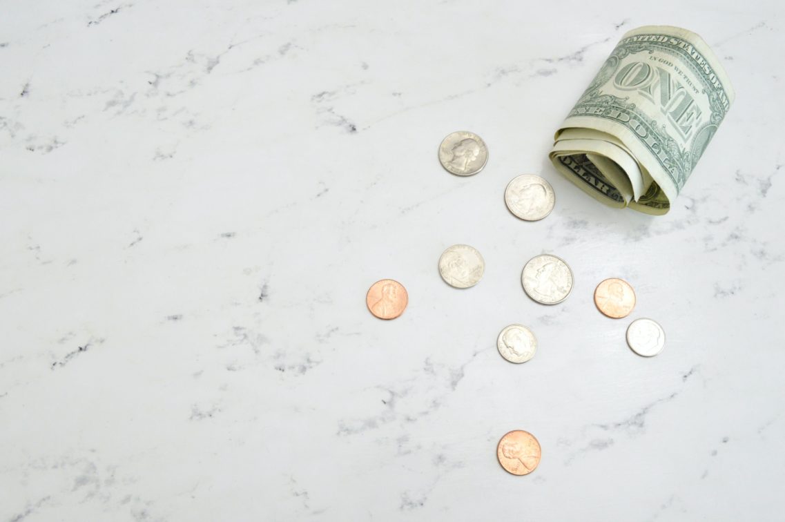 Dollar bills and coins on a white table