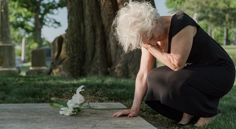 Photo of an Elderly Woman Grieving at a Grave